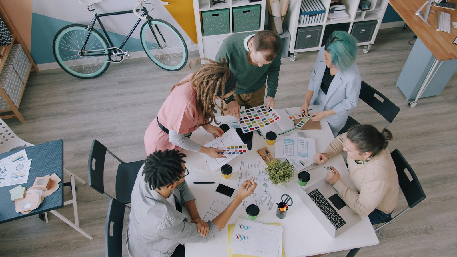 A multidisciplinary team reviewing interface layouts and color systems around a shared table